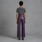 Back view of women's dark purple leather pants falling to a full-length hem