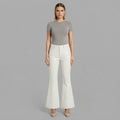 Front view of women's white flared leather pants with grey tee and nude heels