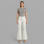 Front view of women's white flared leather pants with grey tee and nude heels